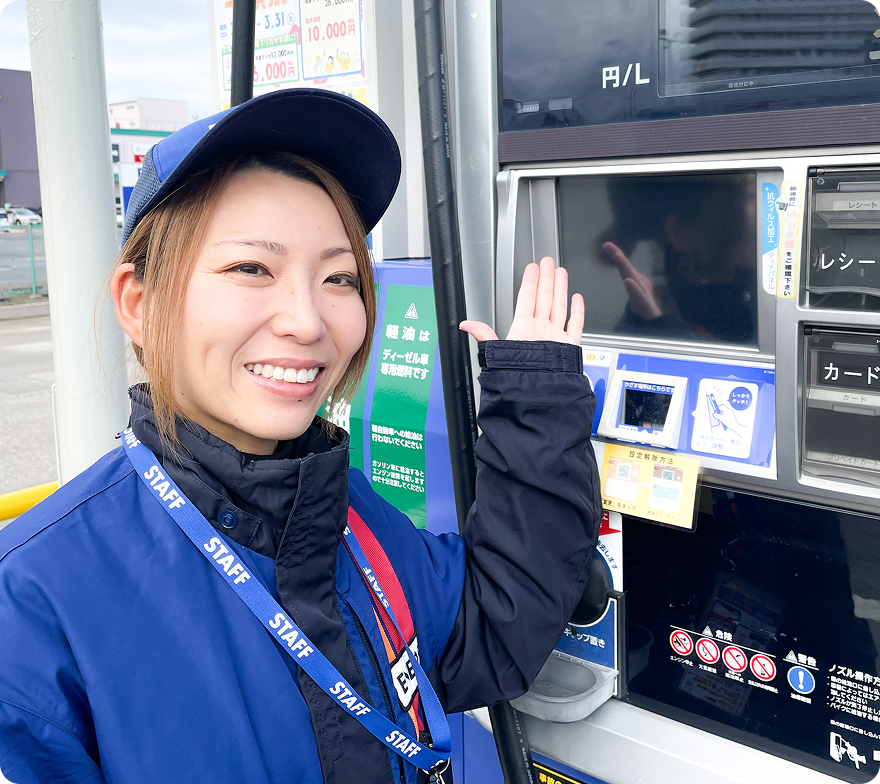 ガソリンスタンドで給油機の使い方をご案内するスタッフ